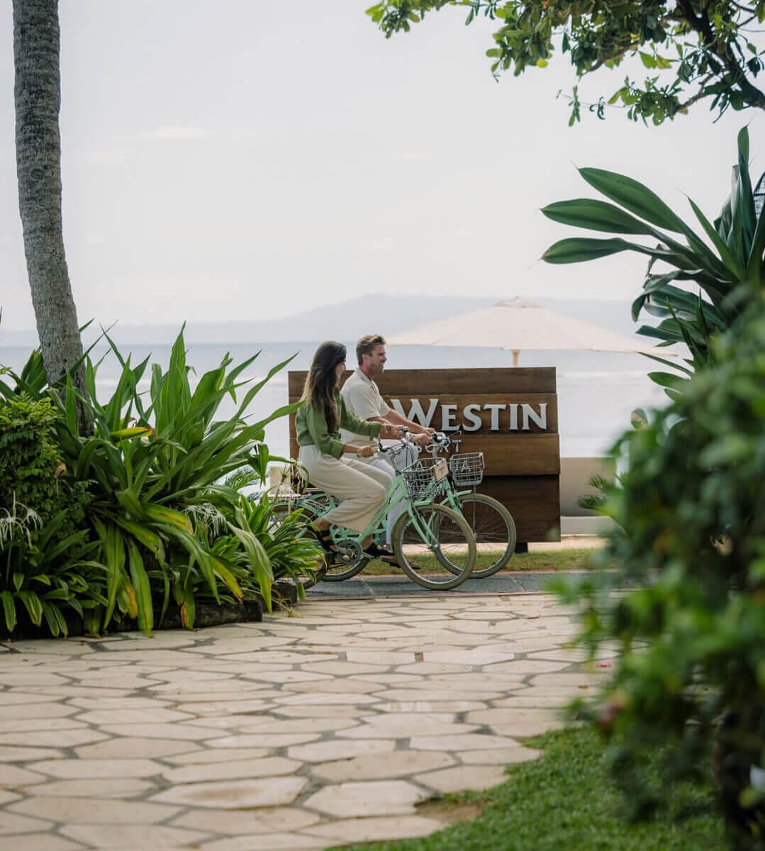 Couples Passing Resort's Sign Using Bike at Beachfront, The Westin Resort Nusa Dua, Bali