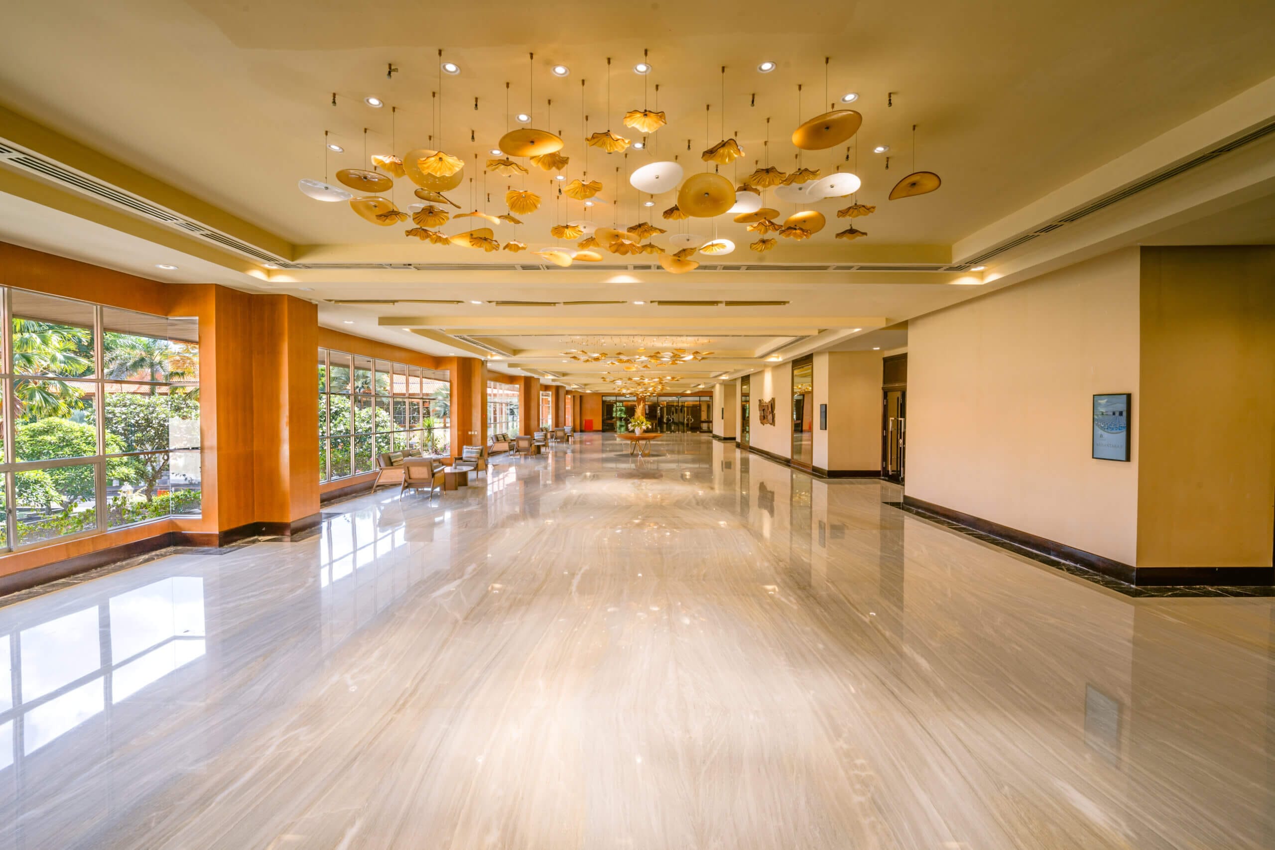 A spacious, elegant foyer with marble floors, large windows, and a ceiling adorned with golden and white hanging decorations.